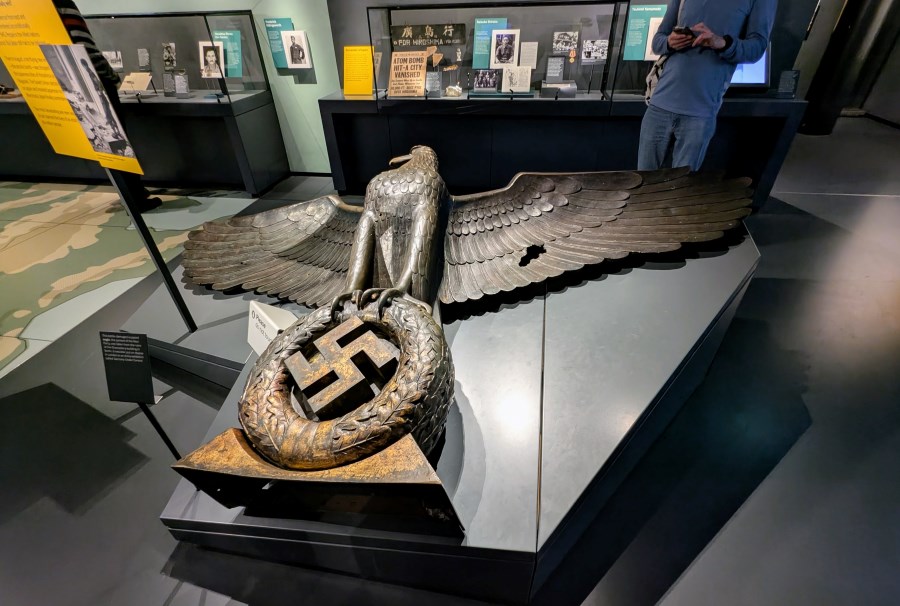 A large metal eagle-clutching-a-wreathed-swastika sculpture displayed lying on the floor