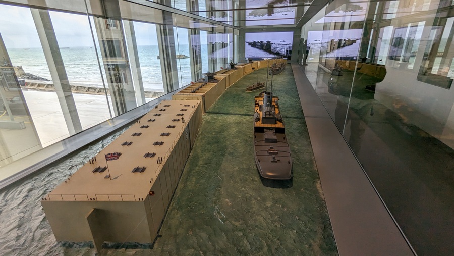 Model of a tugboat steaming past a string of Phoenix caissons