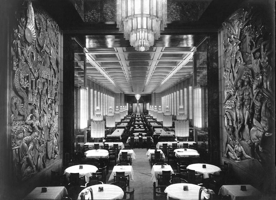 Black & white photo of a large empty dining room with tables set.