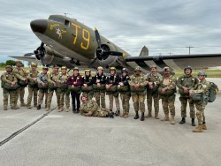 A squad of paratroopers lined up in front of a WW2 C-47 transport plane