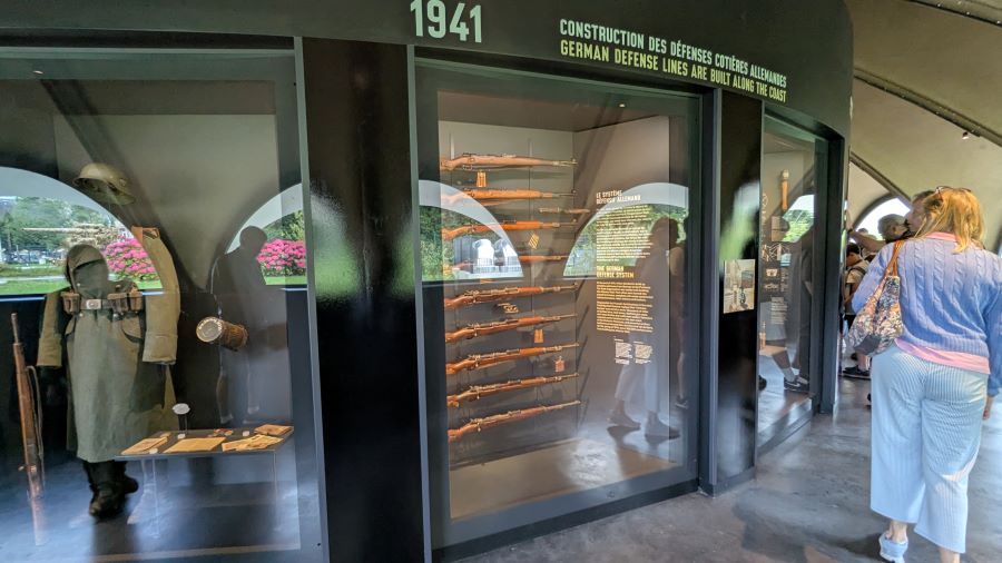 Visitors looking at glass wall cabinet displays of WW2 artefacts
