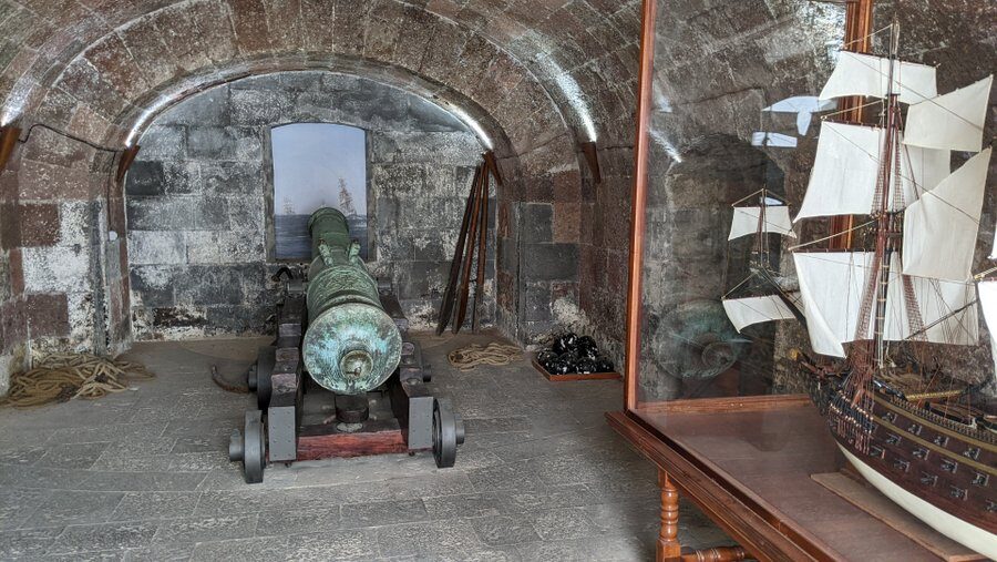 An 18th century cannon pointing out to sea (actually at a painting of the sea!)