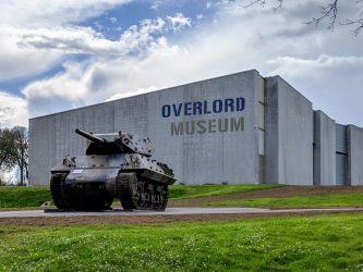 A dark green tank sits in front of a modern museum building