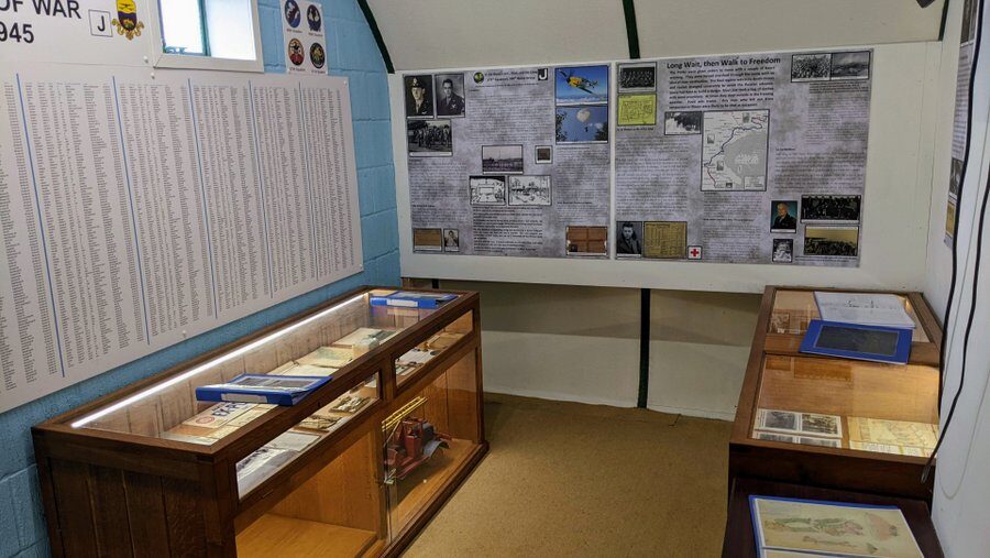 A small room with display cabinets and photo displays relating to captured 390th BG airmen