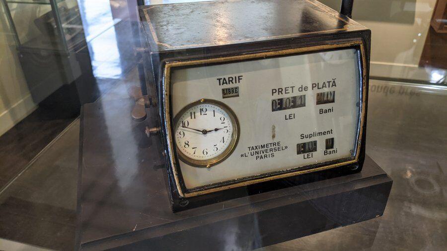 An early taxi meter in an elegant black box with a gold frame around the screen