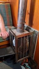 Pat Lawless' hand rest on the bunk next to a small metal stove
