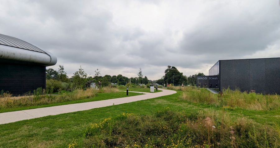 A path runs away from the camera across the grass between the Operation Neptune Building (left) and the WACO building