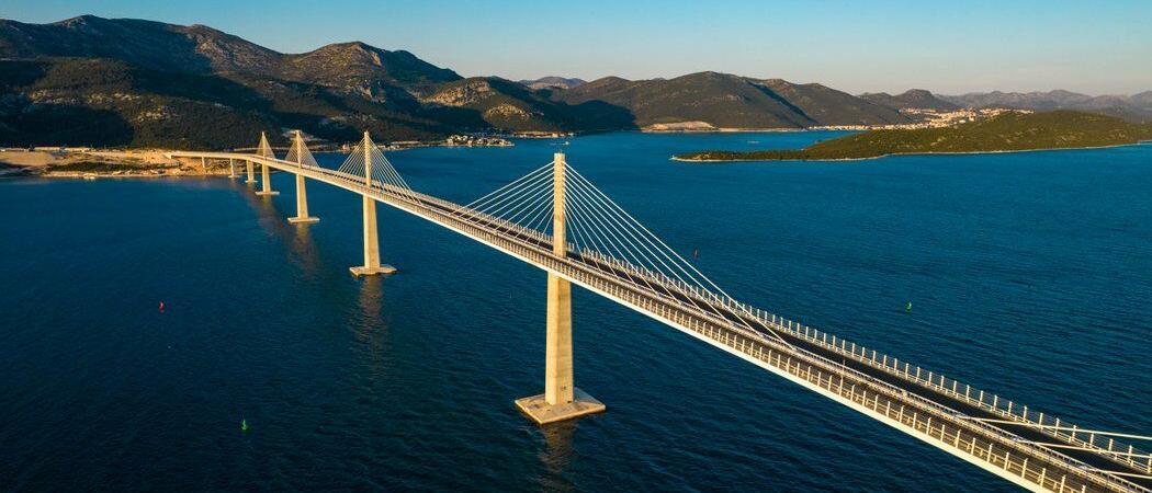 Multi-span Peljesac bridge crosses a blue sea to a mountainous coastline