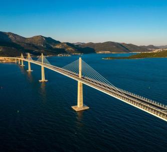 Multi-span Peljesac bridge crosses a blue sea to a mountainous coastline