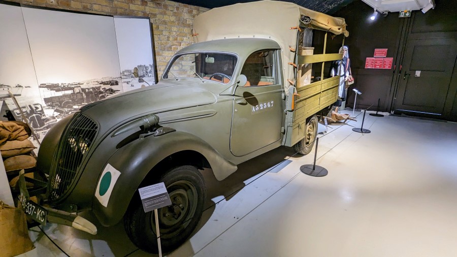 A small green military truck with a canvas enclosed flat bed