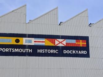 Colourful sign with signal flags on the side of a grey building
