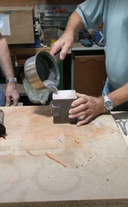 Pouring molten tin into a sand box mold