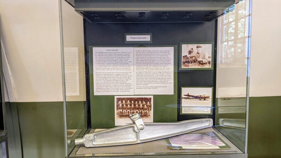 Display case in the 100th BG museum with photographs and a section of silver undercarriage