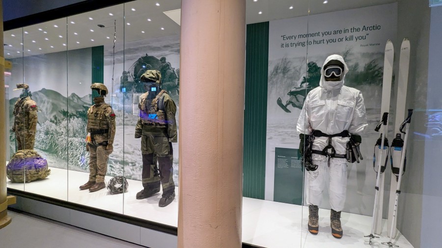 Glass display cabinet with mannequins in different combat gear, including one in winter camouflage and skis