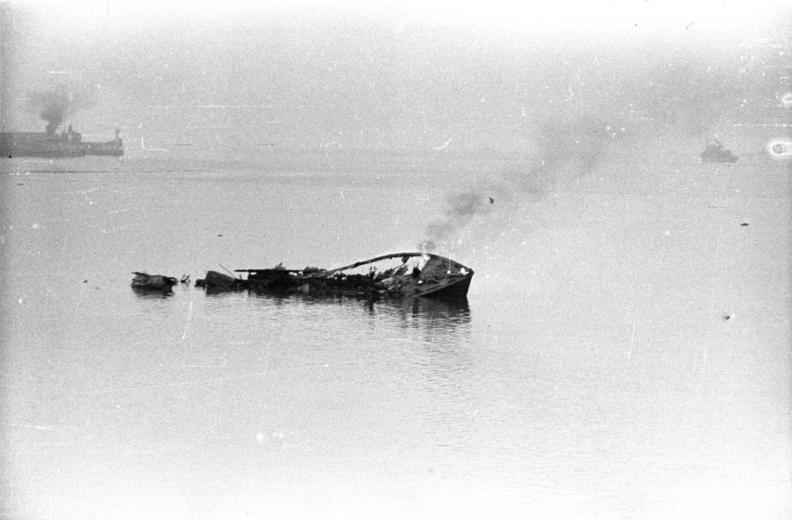 B&W photo of floating wreckage with smoke drifting up from it
