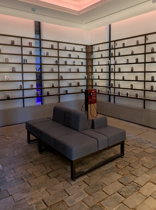 A small room with a bench in the middle and shelves full of small photos on the walls