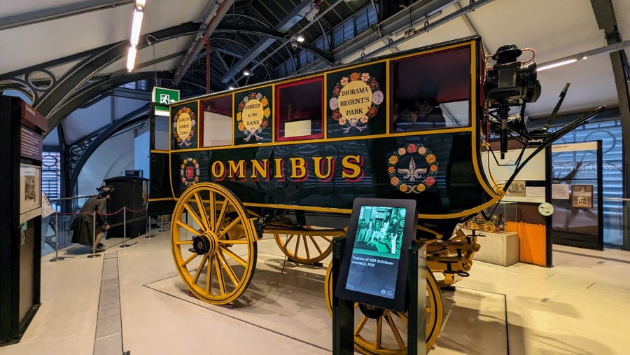 Green painted 4-wheel coach with yellow signage and wheels