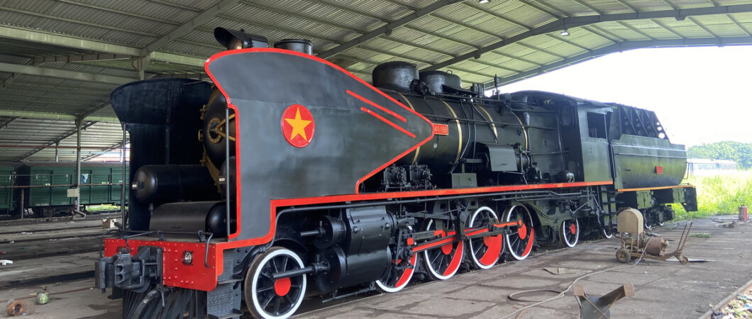 Black steam locomotive with red trim sits in a shed