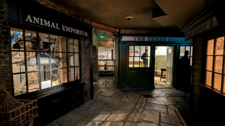 Illuminated shop fronts in the dark alleyways of Sailor Town