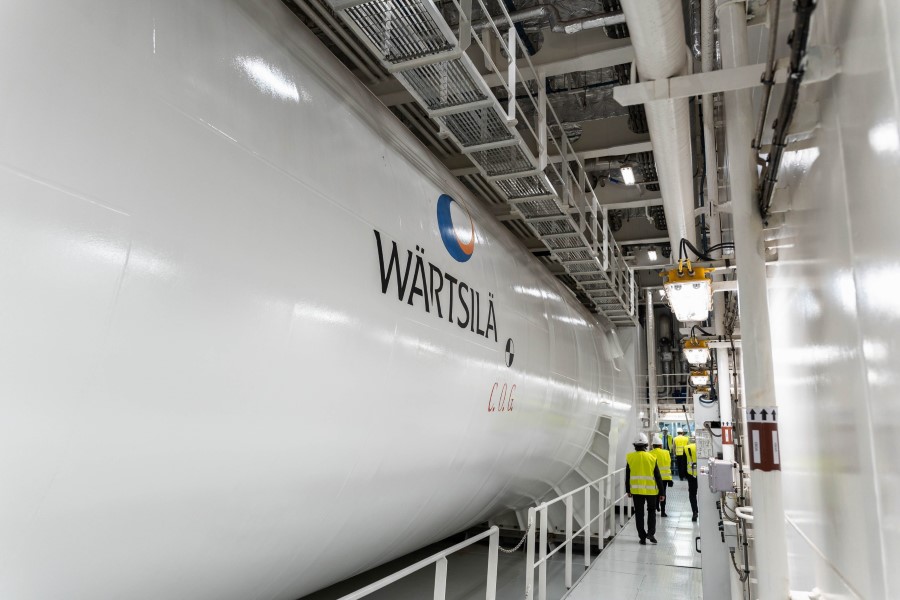 Engineers in hi-vis jackets walking past a large white cylindrical tank