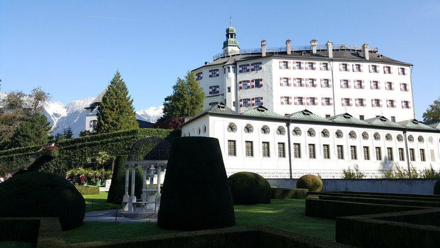 White facade of Schloss Ambras with mountains in background