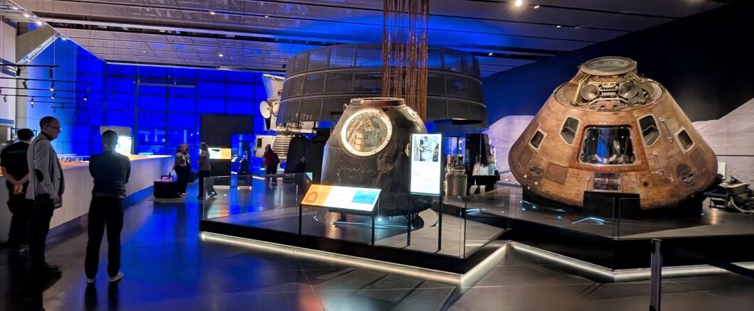 A large gallery of Space exhibits with a group of people talking to one side