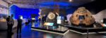 A large gallery of Space exhibits with a group of people talking to one side