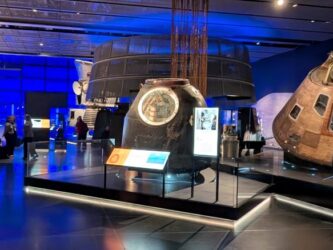 A large gallery of Space exhibits with a group of people talking to one side