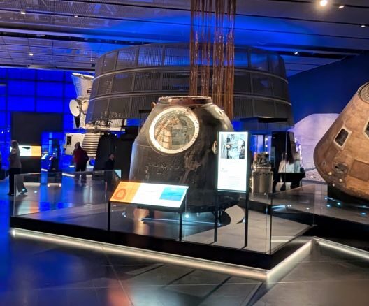 A large gallery of Space exhibits with a group of people talking to one side