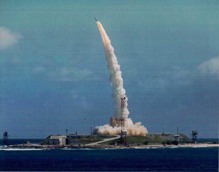 A missile streaks into a blue sky leaving a dense smoke trail