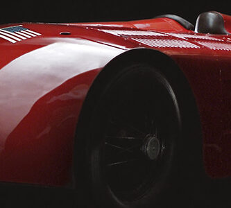 A streamlined classic racing car in glistening red paint. Sunbeam is painted in white letters on the front