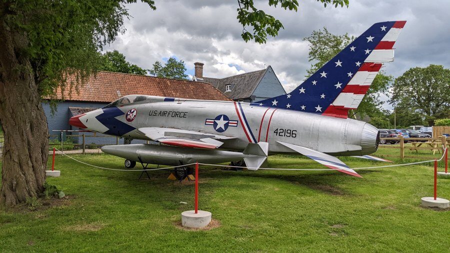 Rear side view of a silver F100 Super Sabre jet in U.S. red, while & blue markings.