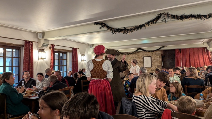 Waiters in 18th century attire perform amid tables of visitors