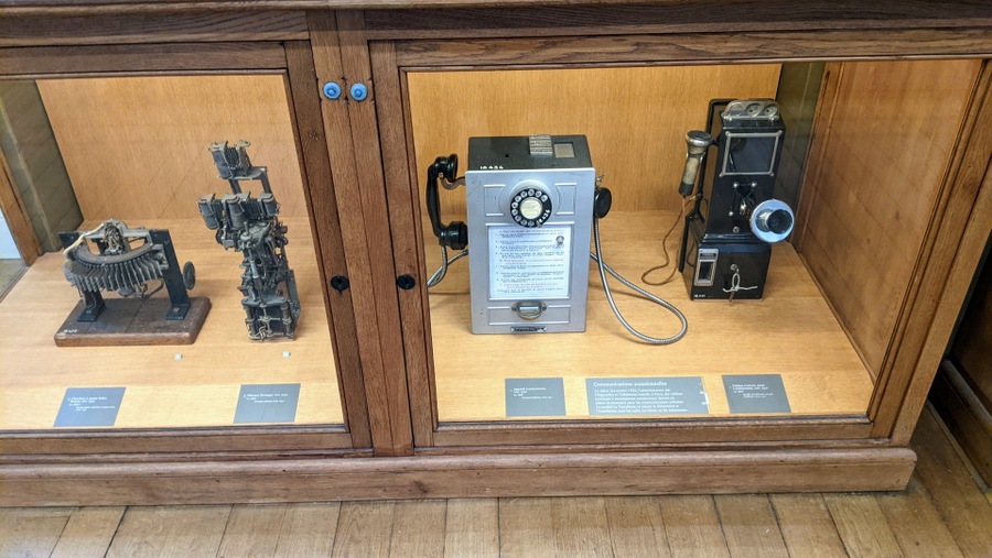 Early rotary dial wall-mounted telephones and switchgear in a display cabinet