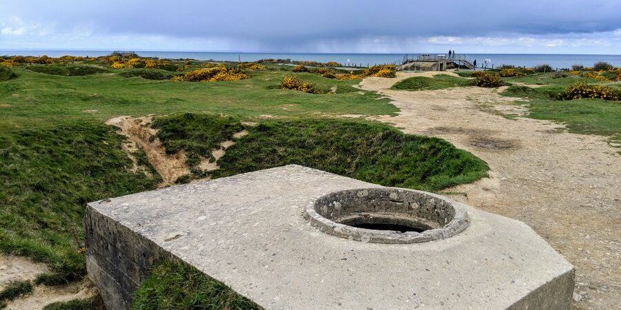 A flat topped concrete bunker amon the green grassed craters, with a hole in the top for a machine gunner