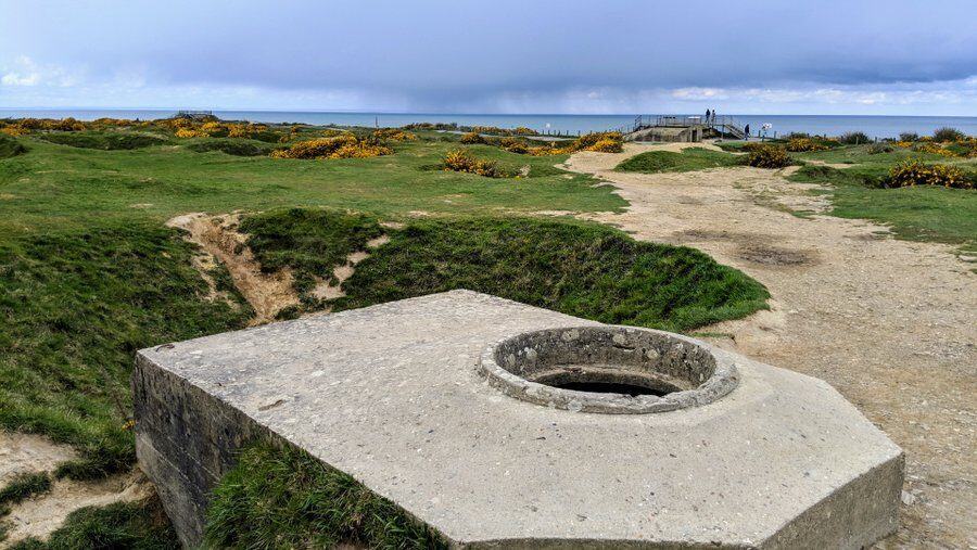 A flat topped concrete bunker amon the green grassed craters, with a hole in the top for a machine gunner