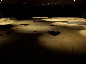 Light brown cloth, with holes, laid out on the floor and lit moodily