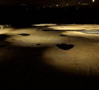 Light brown cloth, with holes, laid out on the floor and lit moodily