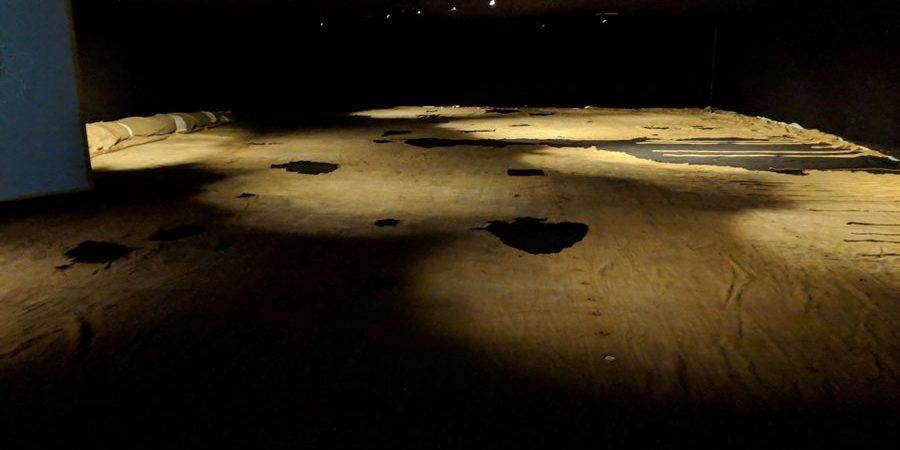 Light brown cloth, with holes, laid out on the floor and lit moodily