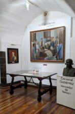 An alcove in the museum with paintings and a table with writing implements and the truce document