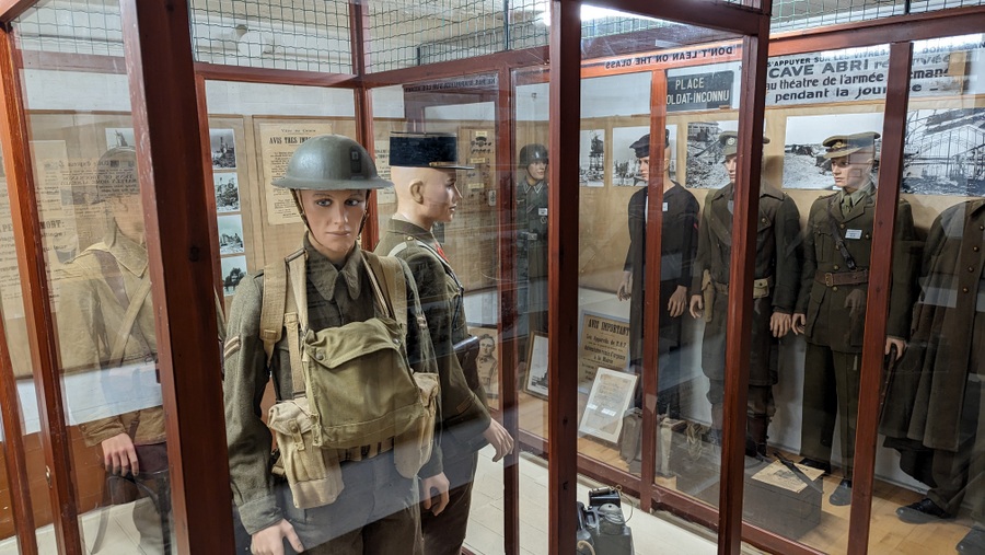 Mannequins wearing different uniforms in glass display cabinets