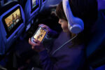 A child plays on their console in their aircraft seat