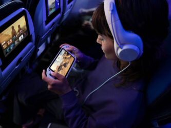 A child plays on their console in their aircraft seat