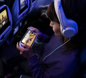 A child plays on their console in their aircraft seat