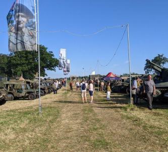 A grassy avenue at We Have Ways Fest with military vehicles displayed on both sides