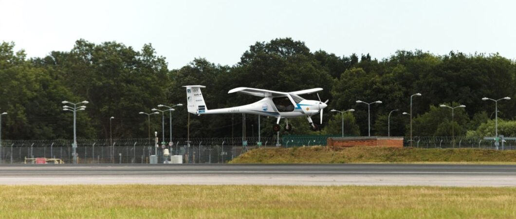 A small and slender light aircraft landing on a large runway
