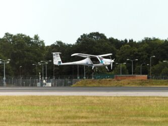 A small and slender light aircraft landing on a large runway