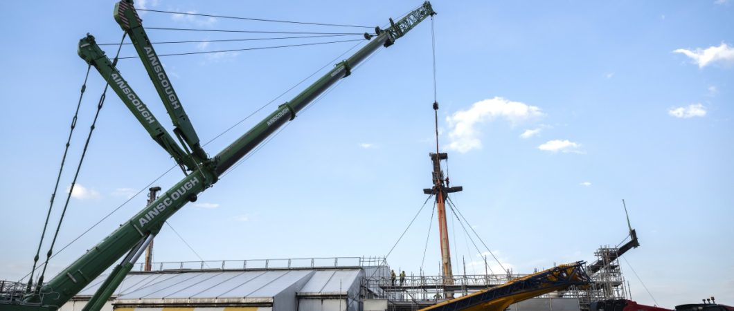 A large crane starts to lift the foremast off HMS Victory
