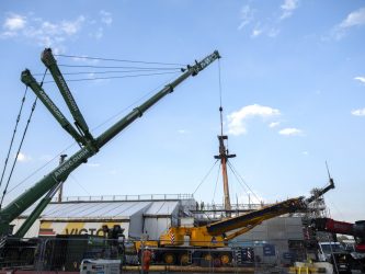 A large crane starts to lift the foremast off HMS Victory
