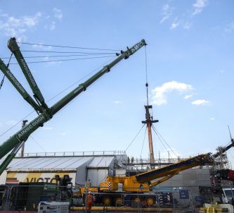 A large crane starts to lift the foremast off HMS Victory
